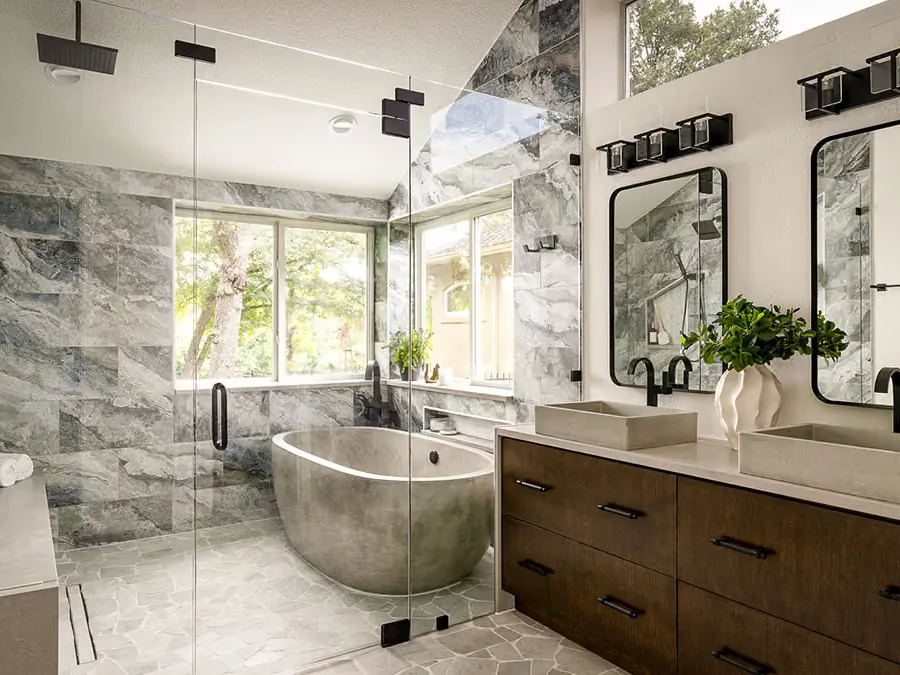 The same Oak Tree bathroom after work, with grey marble walls, a freestanding tub and a dark wood double vanity under the same vaulted ceiling.