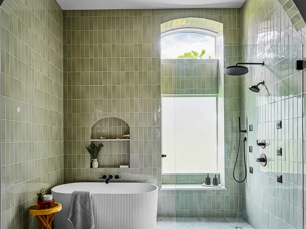 Remodeled Secretariat bathroom with green tiled walls, a freestanding tub, an arched niche and a walk-in shower.